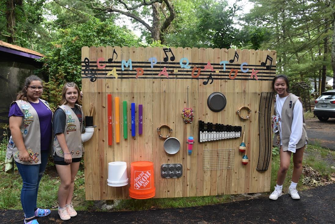Emma S. (purple shirt), Emily B (grey shirt), and Chloe K. (white shirt) show off their recently built musical sound garden installed at Camp Pa-Qua-Tuck.